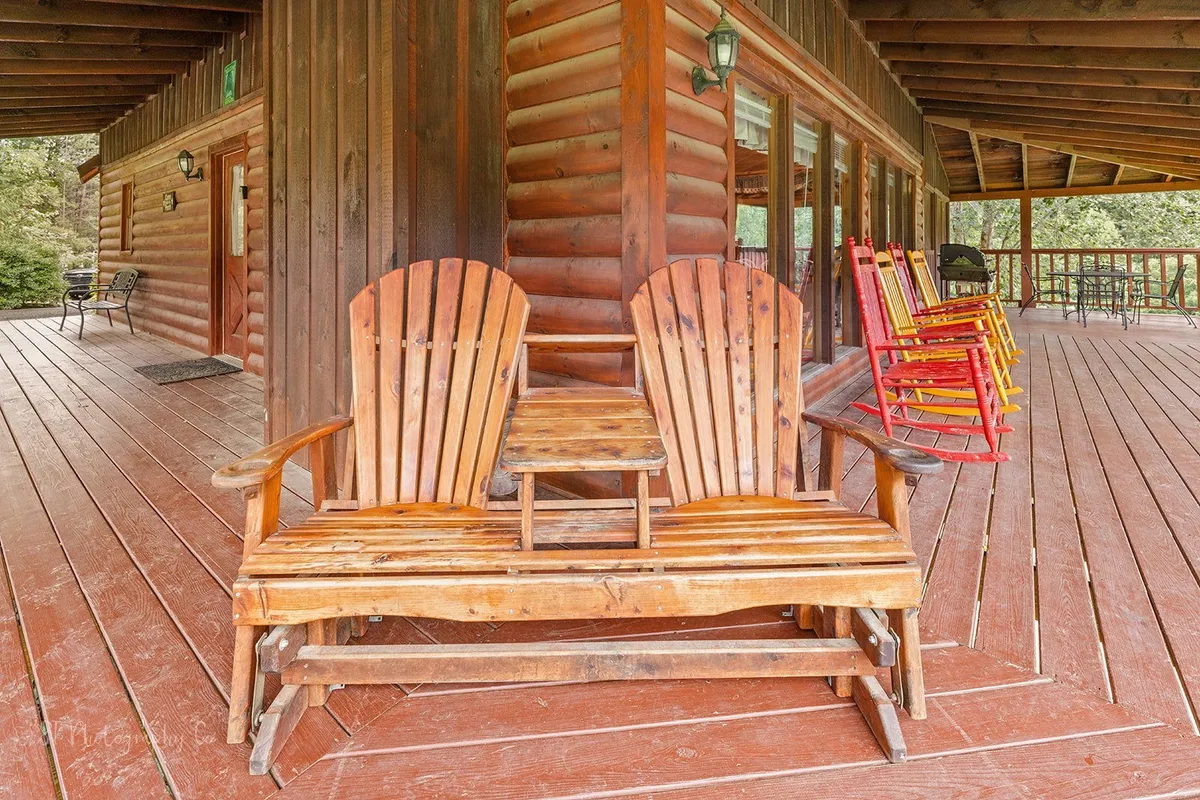 A welcoming outdoor seating area featuring wooden Adirondack chairs and colorful rockers, arranged to encourage conversation and relaxation. The greenery in the background and the casual grouping of chairs evoke a sense of togetherness and laid-back fun.