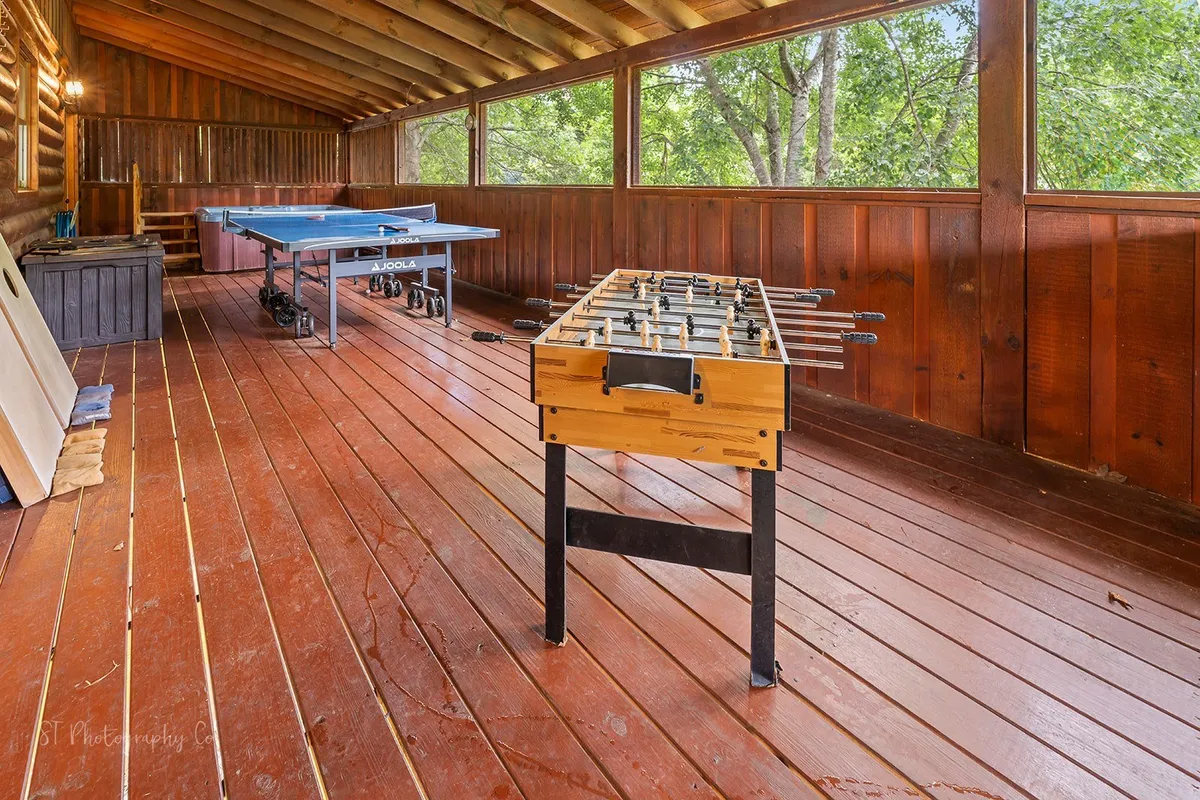 This image showcases a bright, inviting game area with both a foosball table and a ping pong table. The wooden flooring and large windows fill the space with natural light, creating a fun and relaxed atmosphere for group activities.