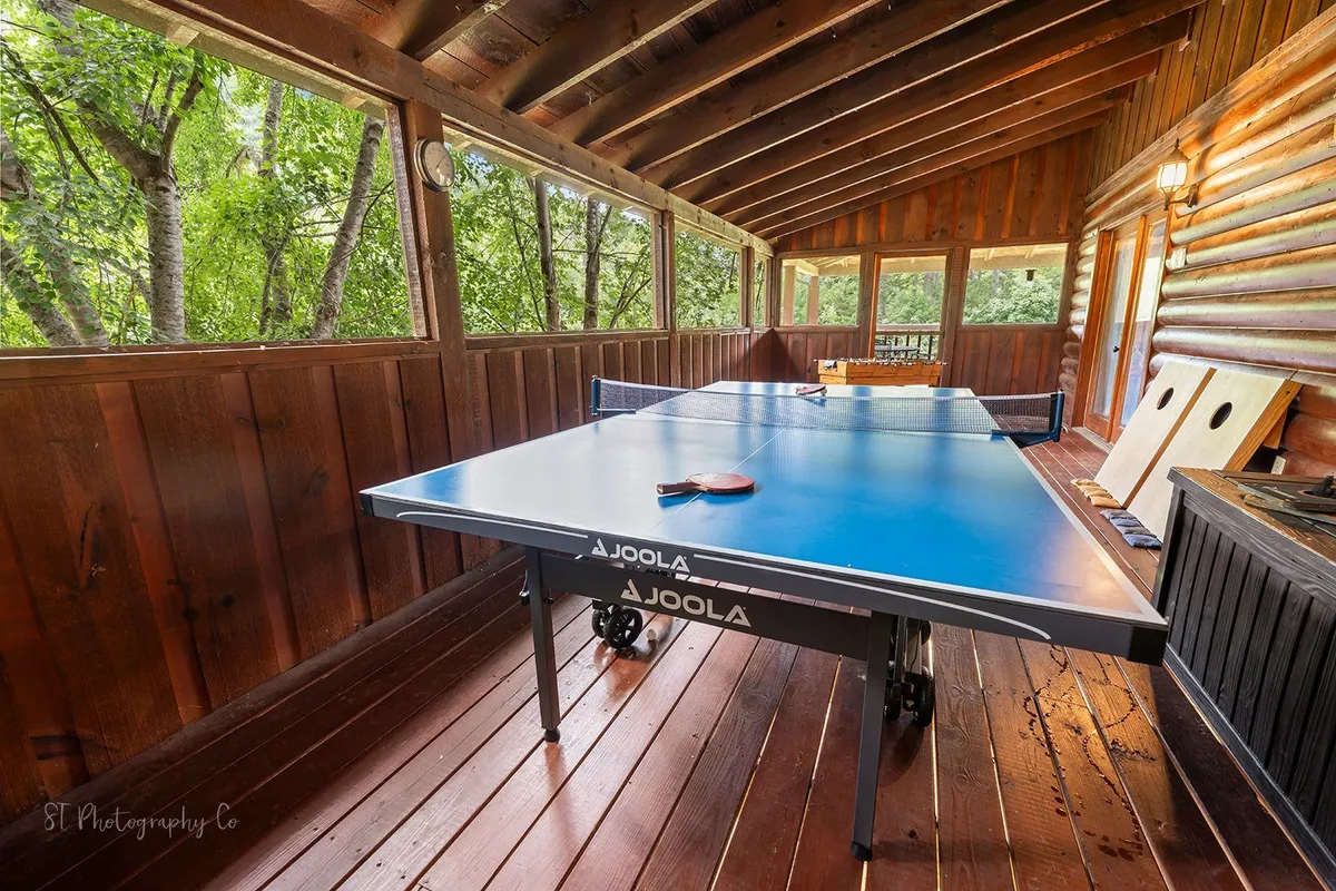 A lively recreation room with a ping pong table, surrounded by wooden walls and large windows that offer glimpses of nature outside. The area feels open and social, ideal for group activities and making new memories.